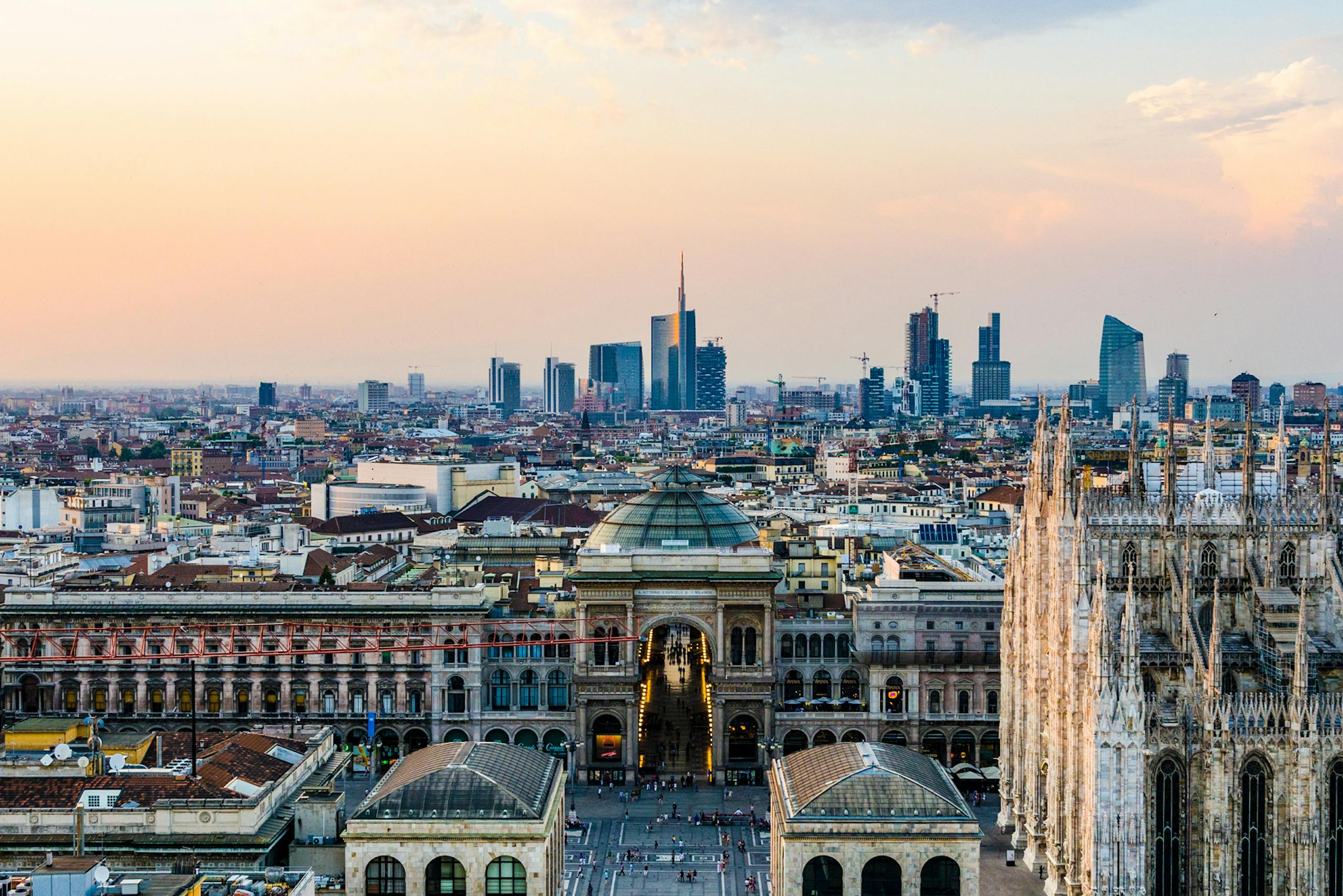 Captivating aerial view of Milan cityscape featuring Galleria Vittorio Emanuele II and modern buildings at sunset.